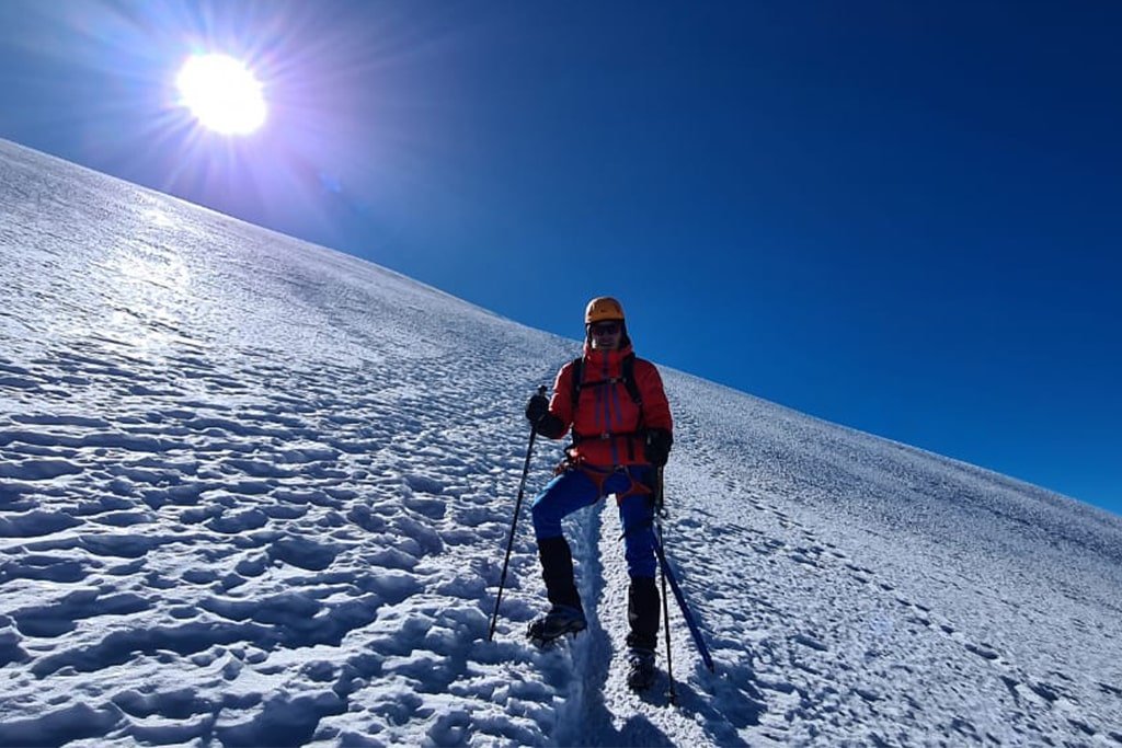 A climber on the sunlit glacier slope