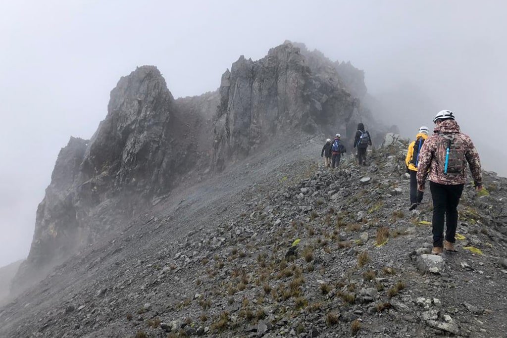 Hikers climbing a rocky ridge in the clouds