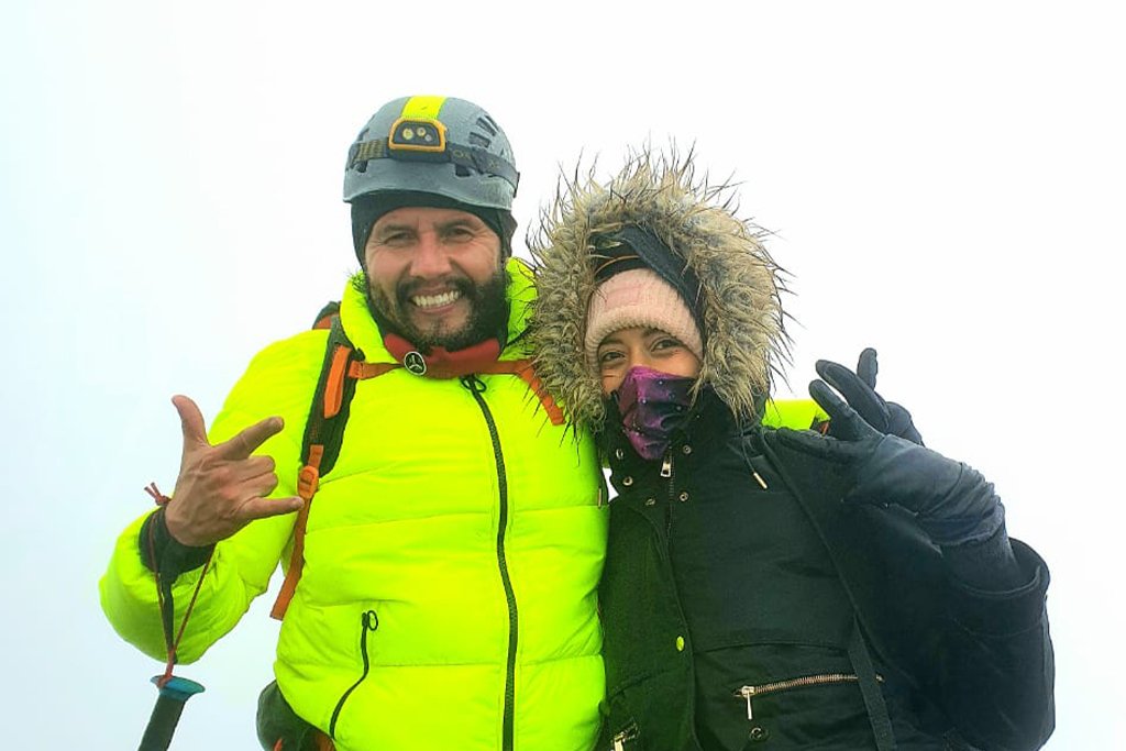 Two hikers celebrating on a cold, cloudy summit